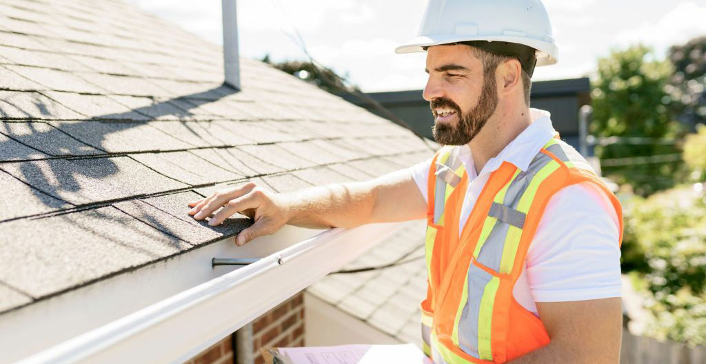 Technicien inspectant une façade avant installation d'auvent photovoltaïque avec outil de mesure